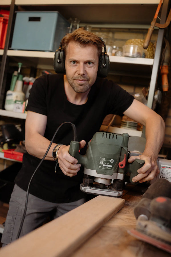 Alex met bovenfrees en gehoorbescherming in zijn werkplaats